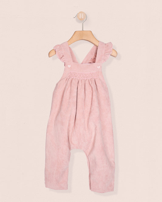 Pink children's overalls on a hanger against a light pink background