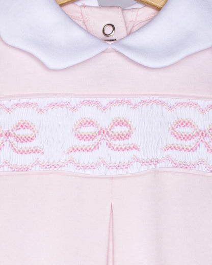 Close-up of a pink garment with white collar and embroidered details on a white background