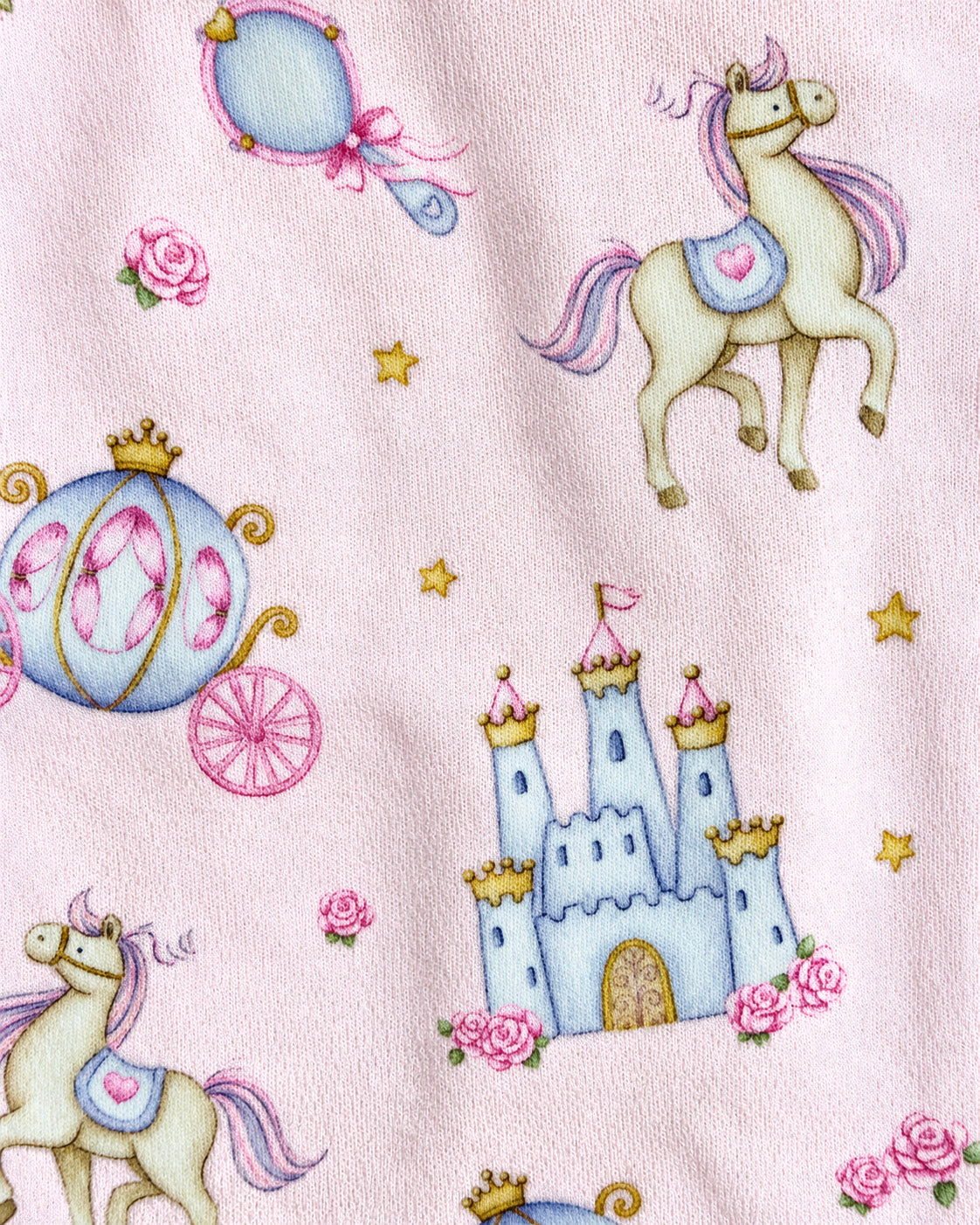 A close-up of a light pink fabric featuring a whimsical fairy tale print with cream-colored horses, a blue carriage, a blue castle, pink roses, and small gold stars.