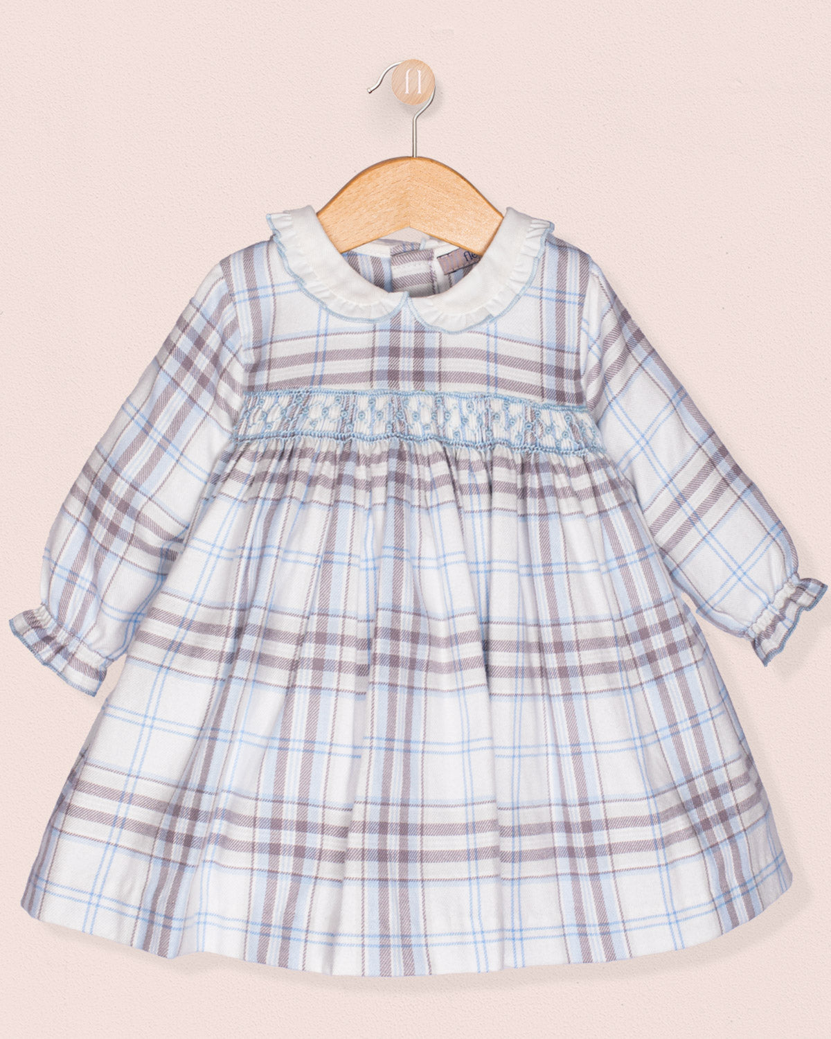 Plaid dress on a wooden hanger against a light pink background