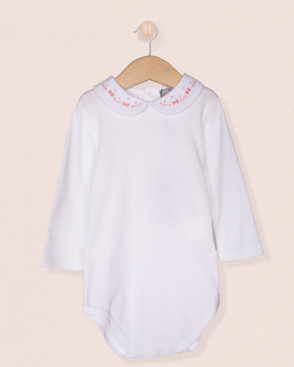 White baby dress with pink trim on a beige background