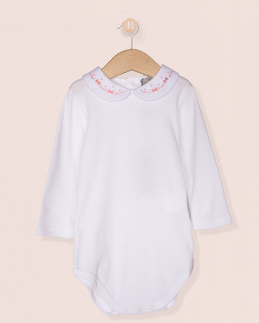 White baby dress with pink trim on a beige background