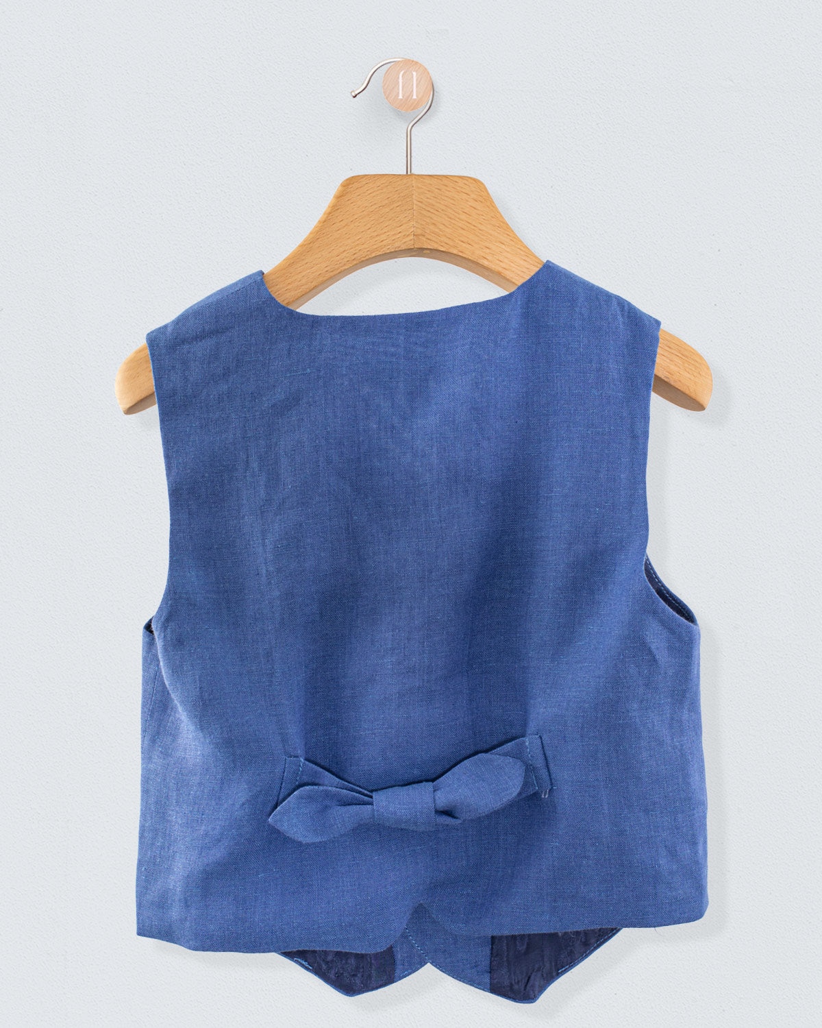 Back view of Prince Harry blue linen vest featuring a decorative bow at the waist, shown on hanger