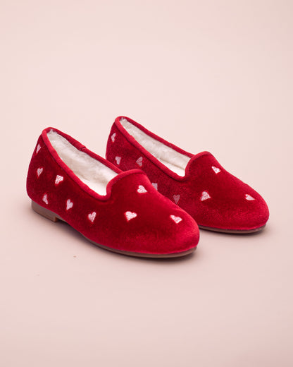 Red velvet slippers with heart patterns on a beige background