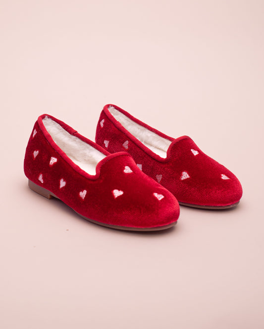 Red velvet slippers with heart patterns on a beige background