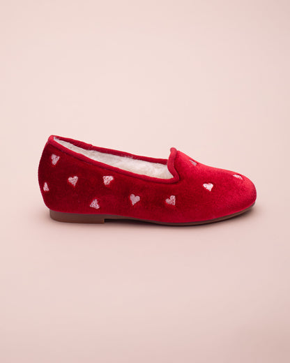 Red shoe with heart patterns on a beige background