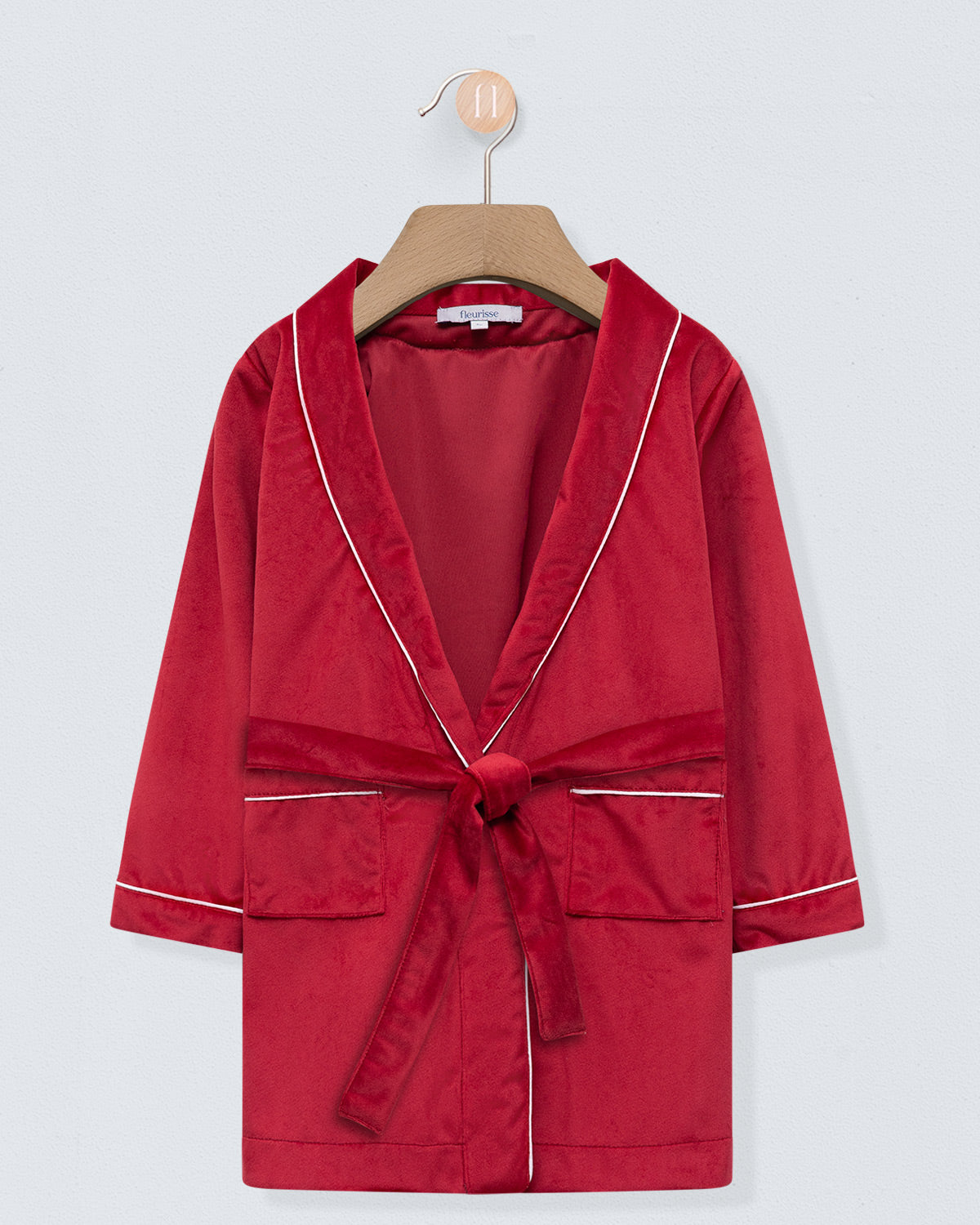 Red robe with white trim on a wooden hanger against a light gray background