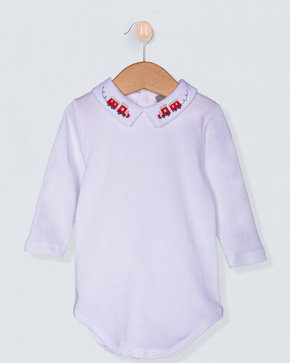 White baby shirt with embroidered train on collar on a hanger against a light gray background