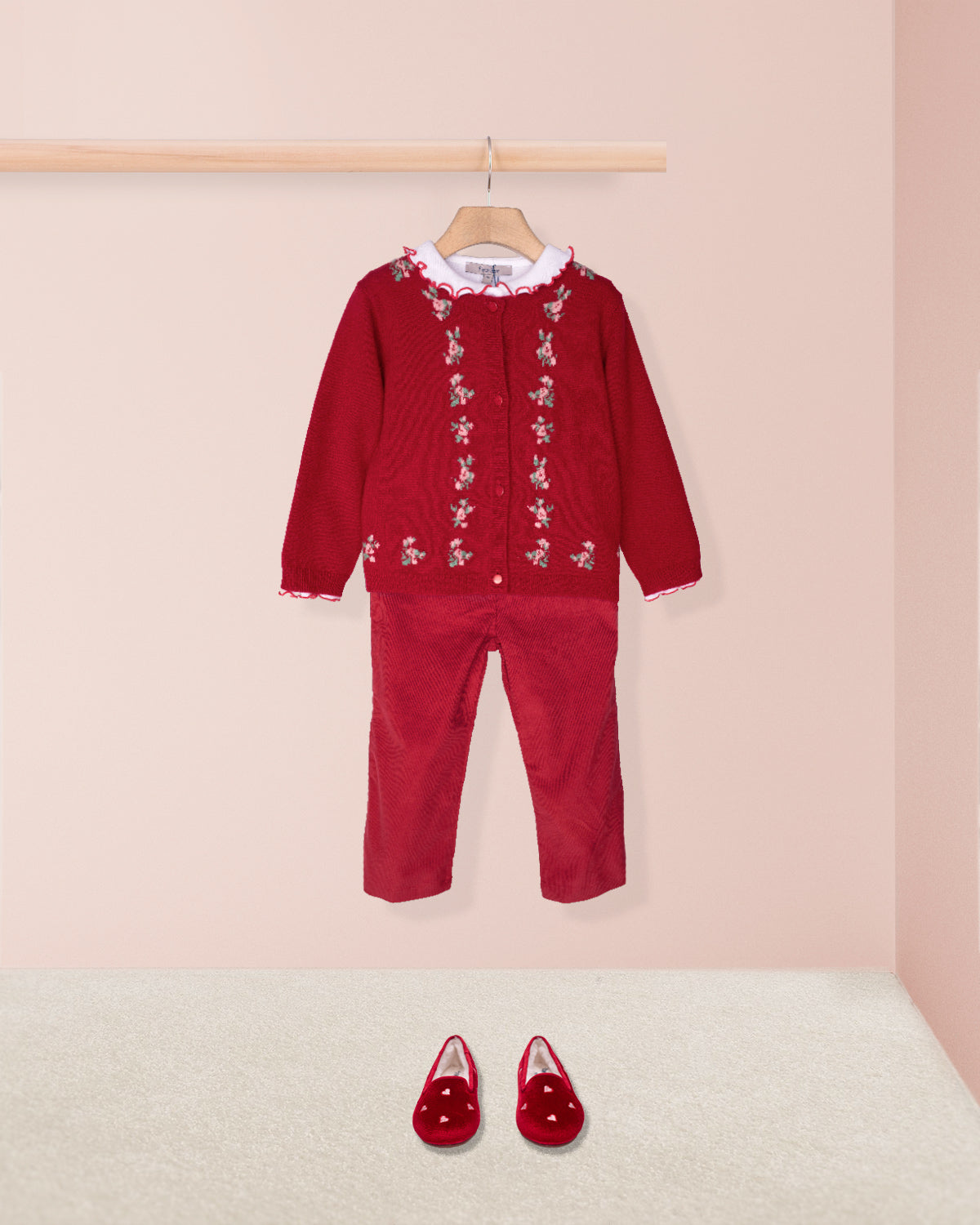 Red children's outfit with matching shoes on a pink background