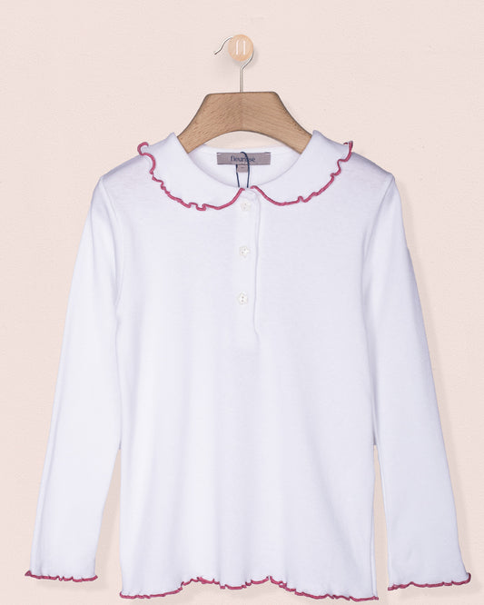 White blouse with pink trim on a hanger against a beige background