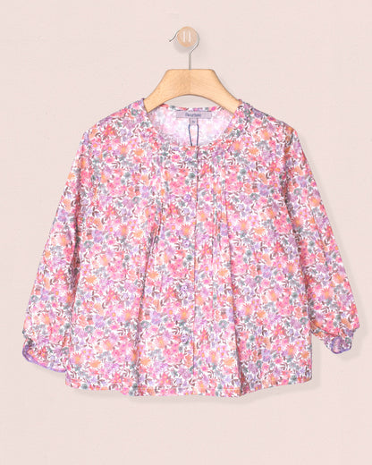 Floral patterned blouse on a hanger against a beige background