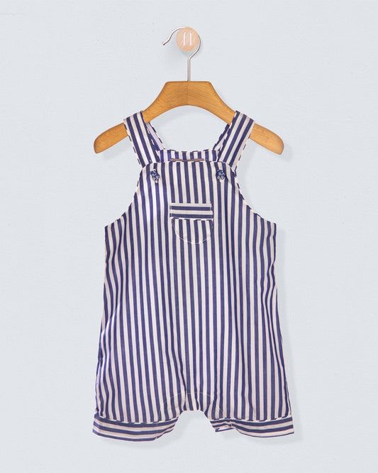 Striped overalls hanging on a wooden hanger against a light gray background