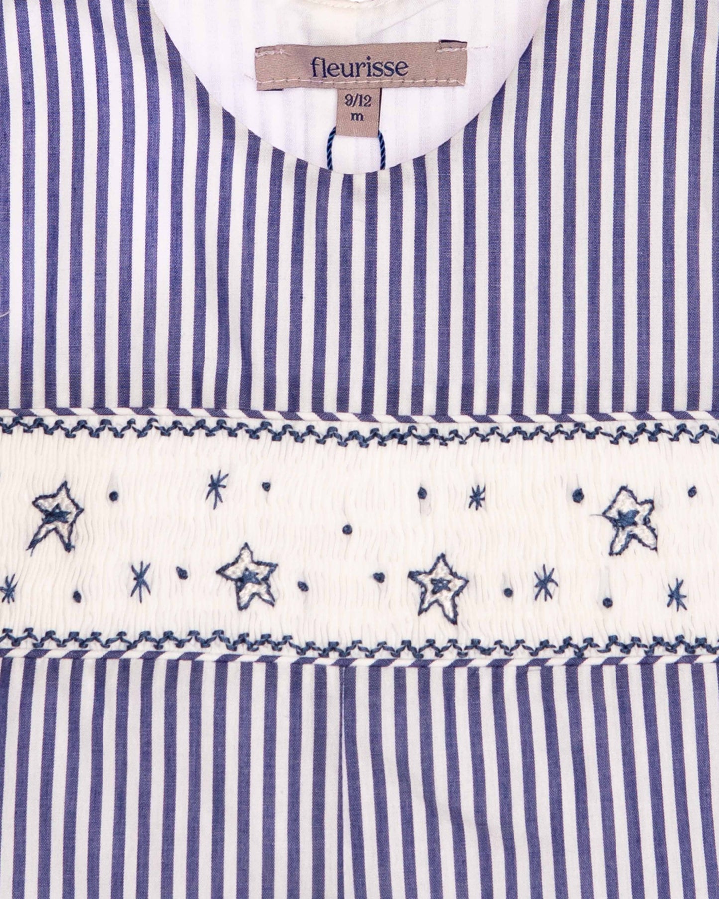 close up fabric of Blue and white striped dress with star patterns and 'fleurisse' label.