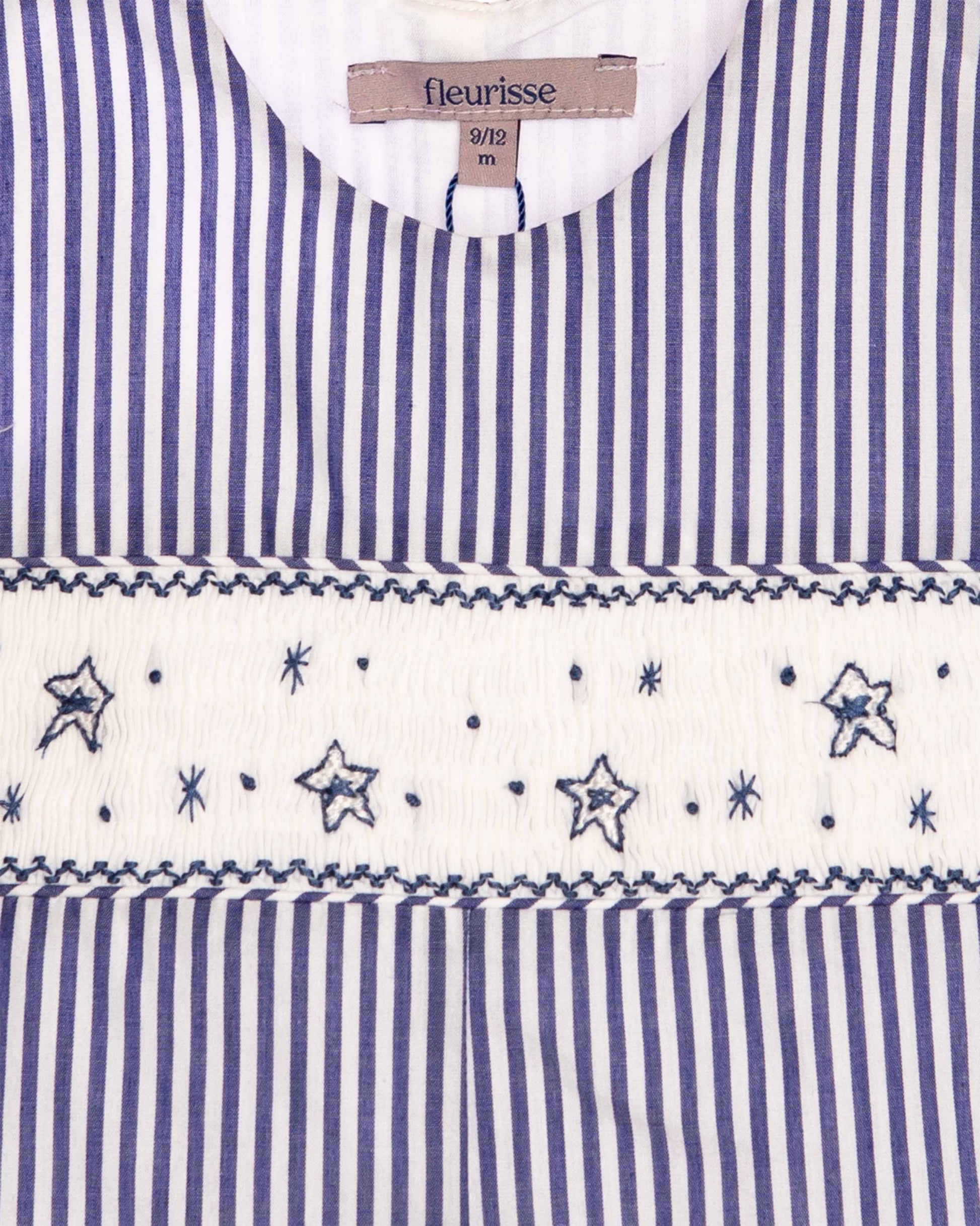 close up fabric of Blue and white striped dress with star patterns and 'fleurisse' label.