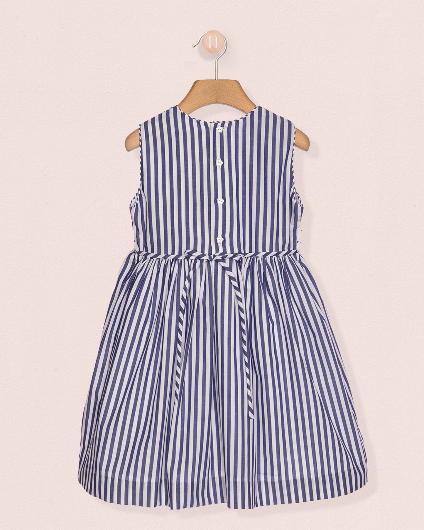 Blue and white striped dress on a hanger against a beige background