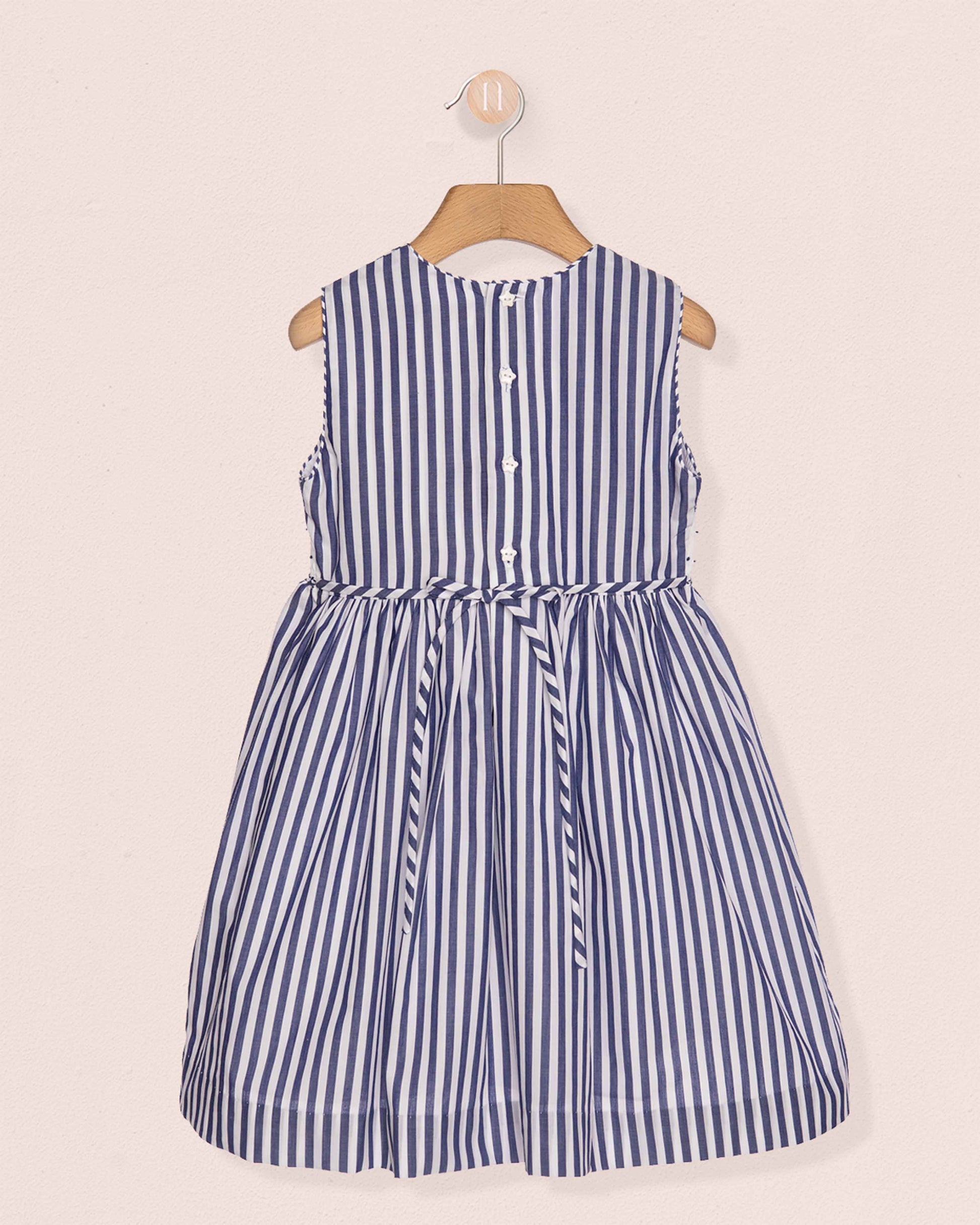 Blue and white striped dress on a hanger against a beige background