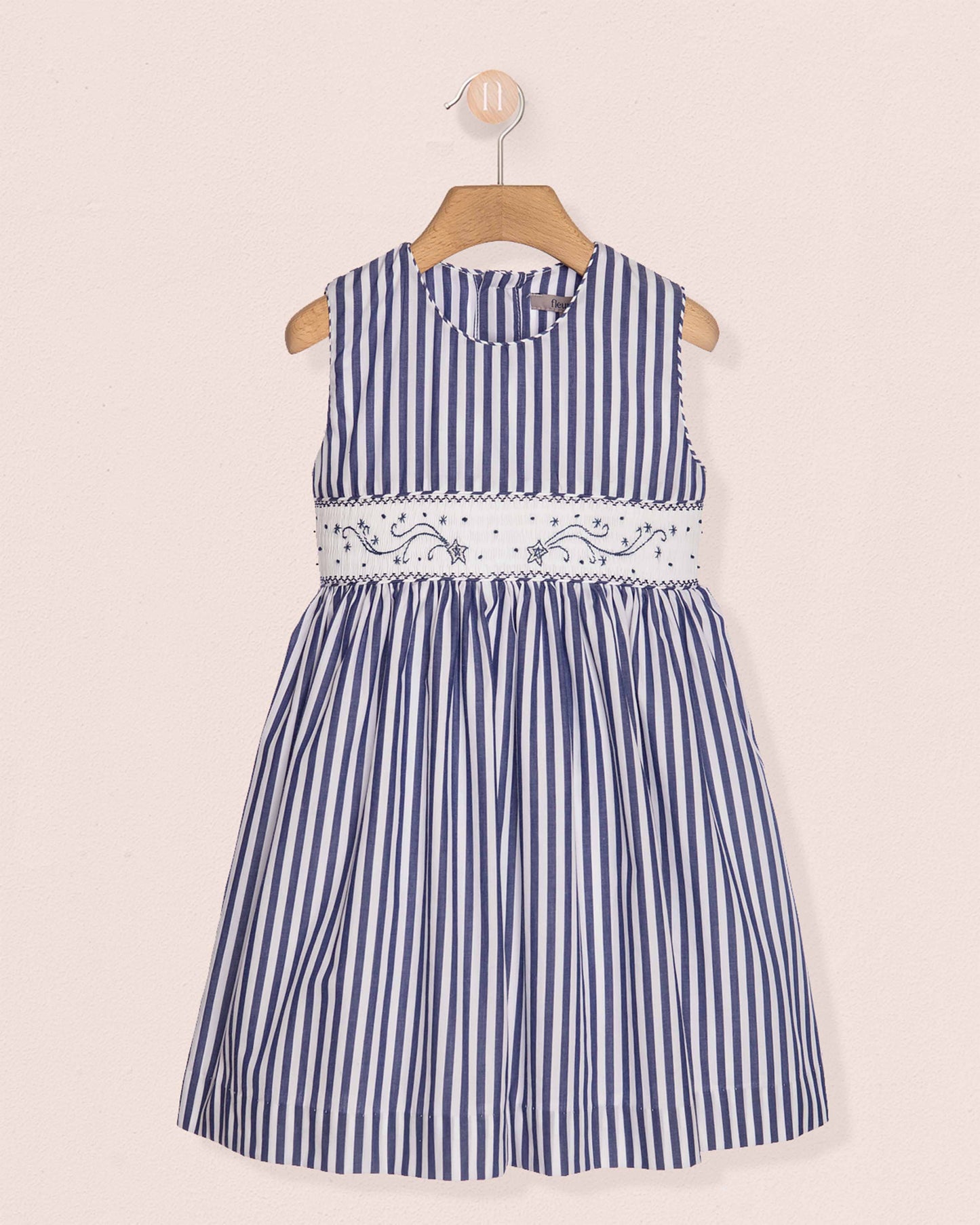 Blue and white striped dress with floral embroidery on a beige background
