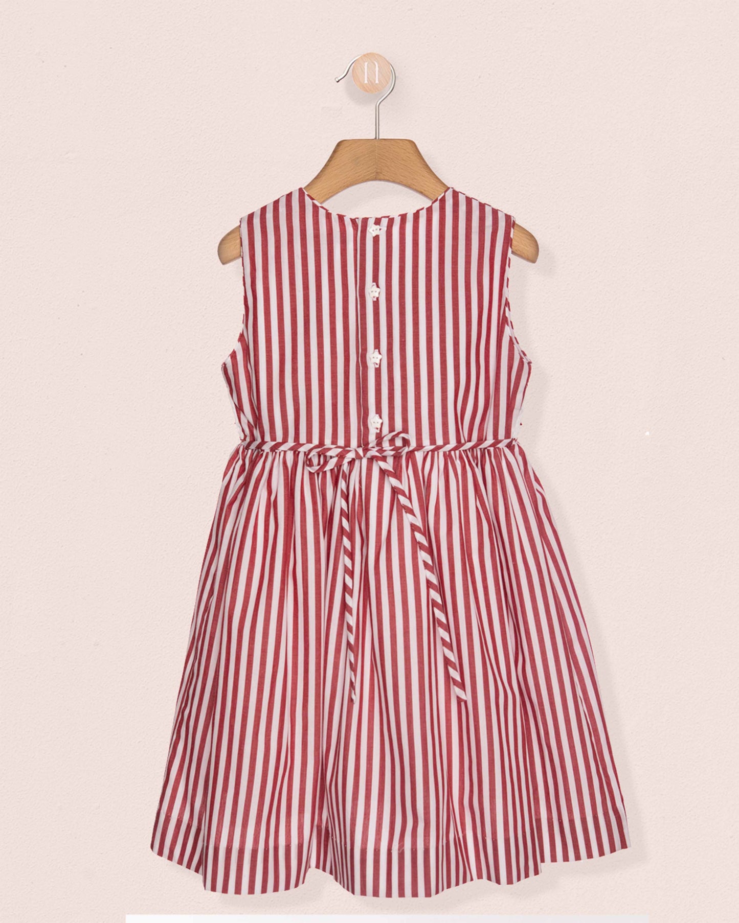 Red and white striped dress on a hanger against a light pink background