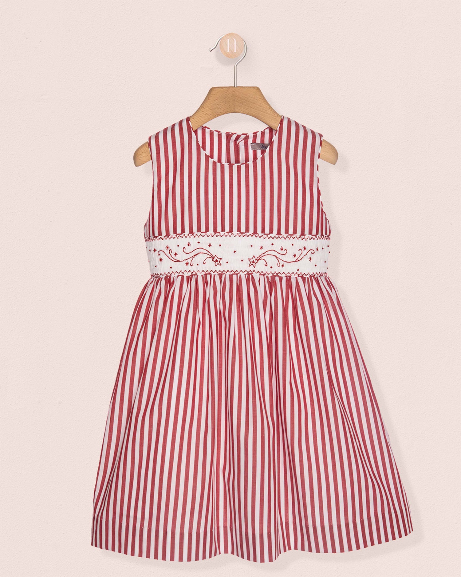Red and white striped dress on a hanger against a light pink background