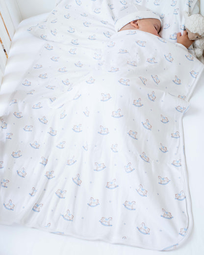 Baby model sleeping in a crib- wrapped in Pima Blue Rocking Horse Blanket