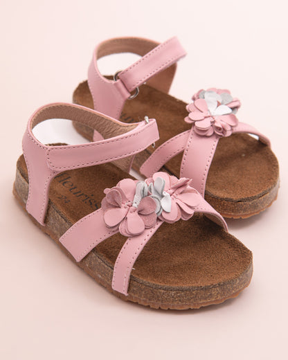 Pair of blush pink leather toddler sandals with floral appliqué and velcro straps, displayed on a light pink background.