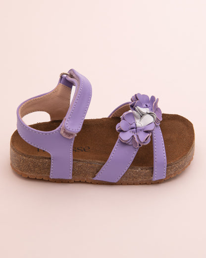 Side view of a single toddler lavender leather sandal with cork footbed, flower detailing on the front strap, and velcro ankle strap closure.