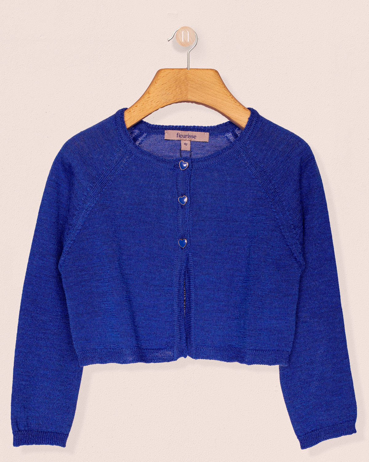 Blue cardigan on a wooden hanger against a beige background