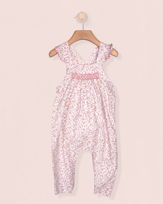 Floral-patterned jumpsuit on a hanger against a light pink background