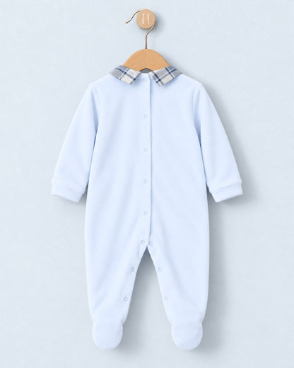 A baby long-sleeve footed sleeper in light blue, featuring a plaid collar and snap-button front, hanging on a wooden hanger against a light gray background.