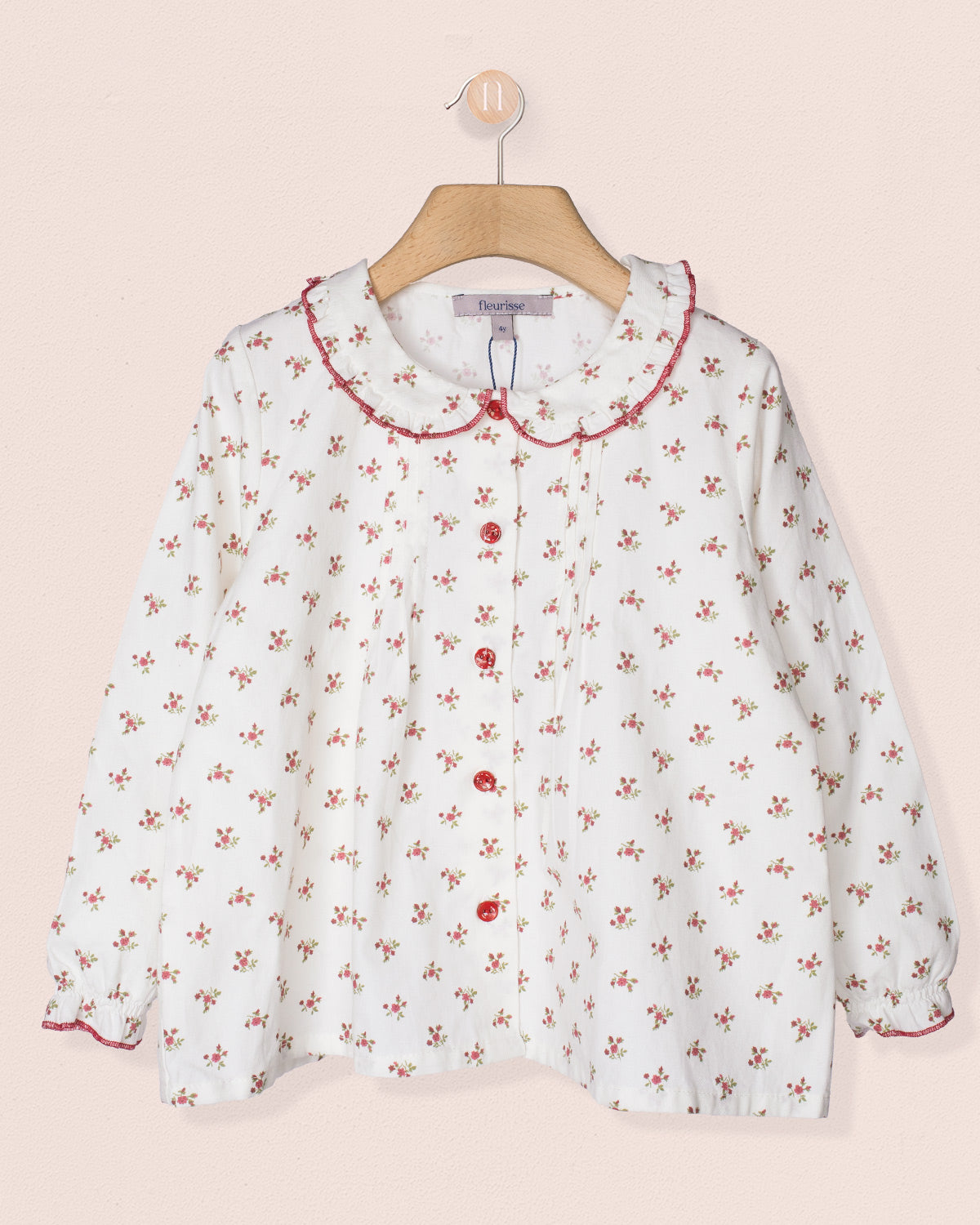 White blouse with red floral pattern on a beige background