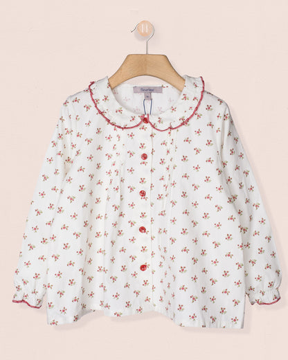 White blouse with red floral pattern on a beige background