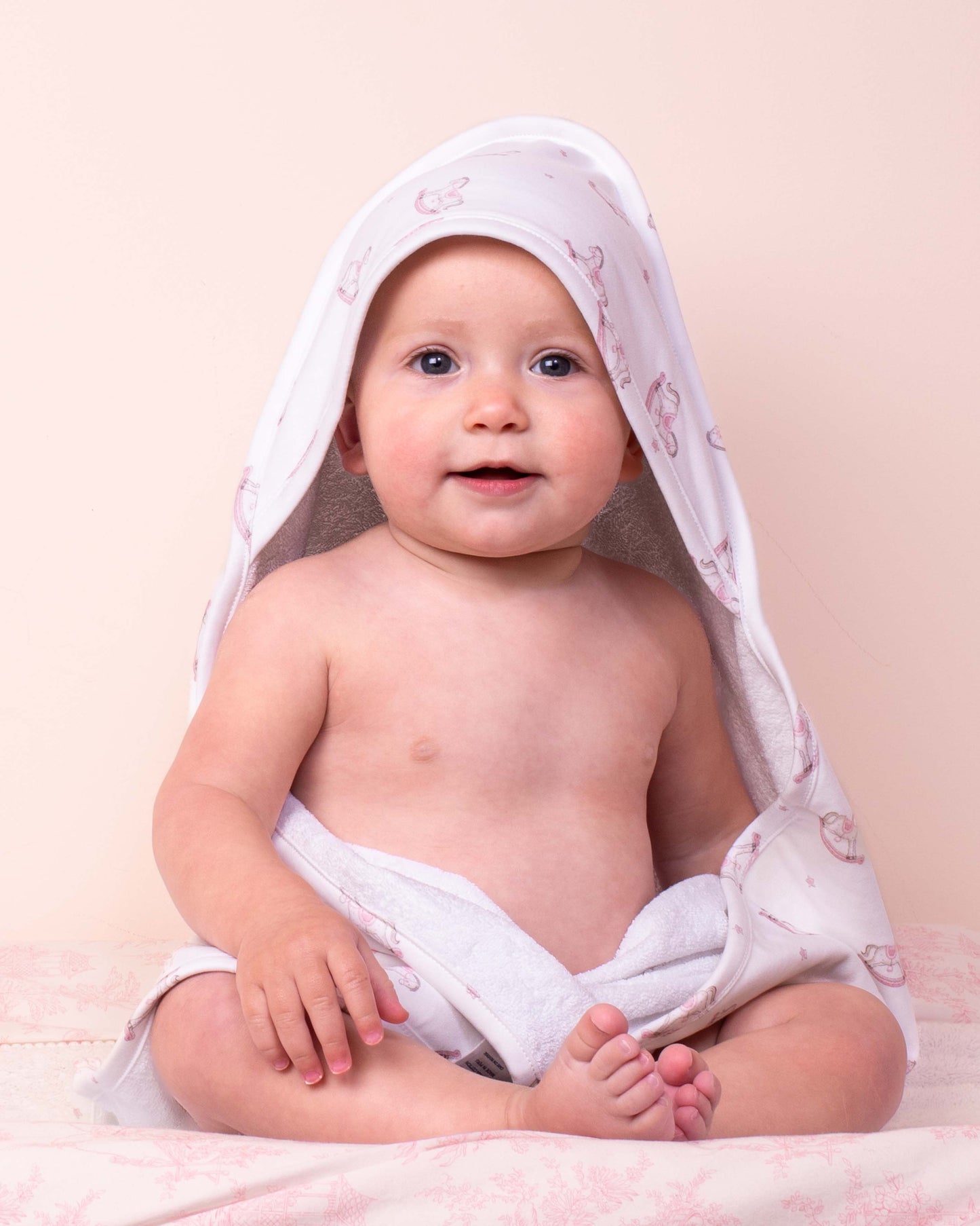 Baby model wrapped in Pima Pink Rocking Horse hooded towel 