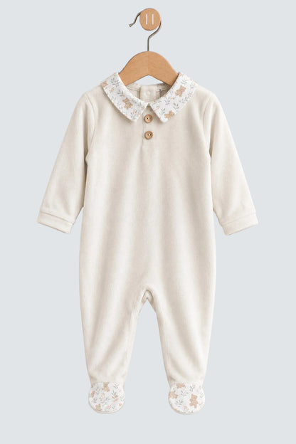 An off-white baby footed jumpsuit with a lace Peter Pan collar and decorative buttons, hanging on a wooden hanger against a light gray background.