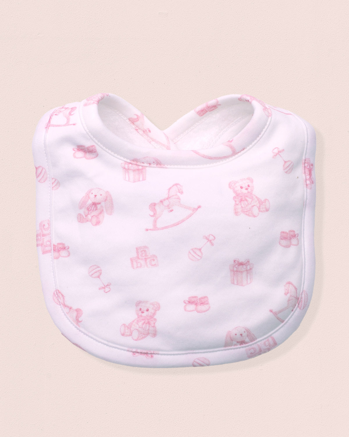 White bib with pink teddy bear pattern on a beige background