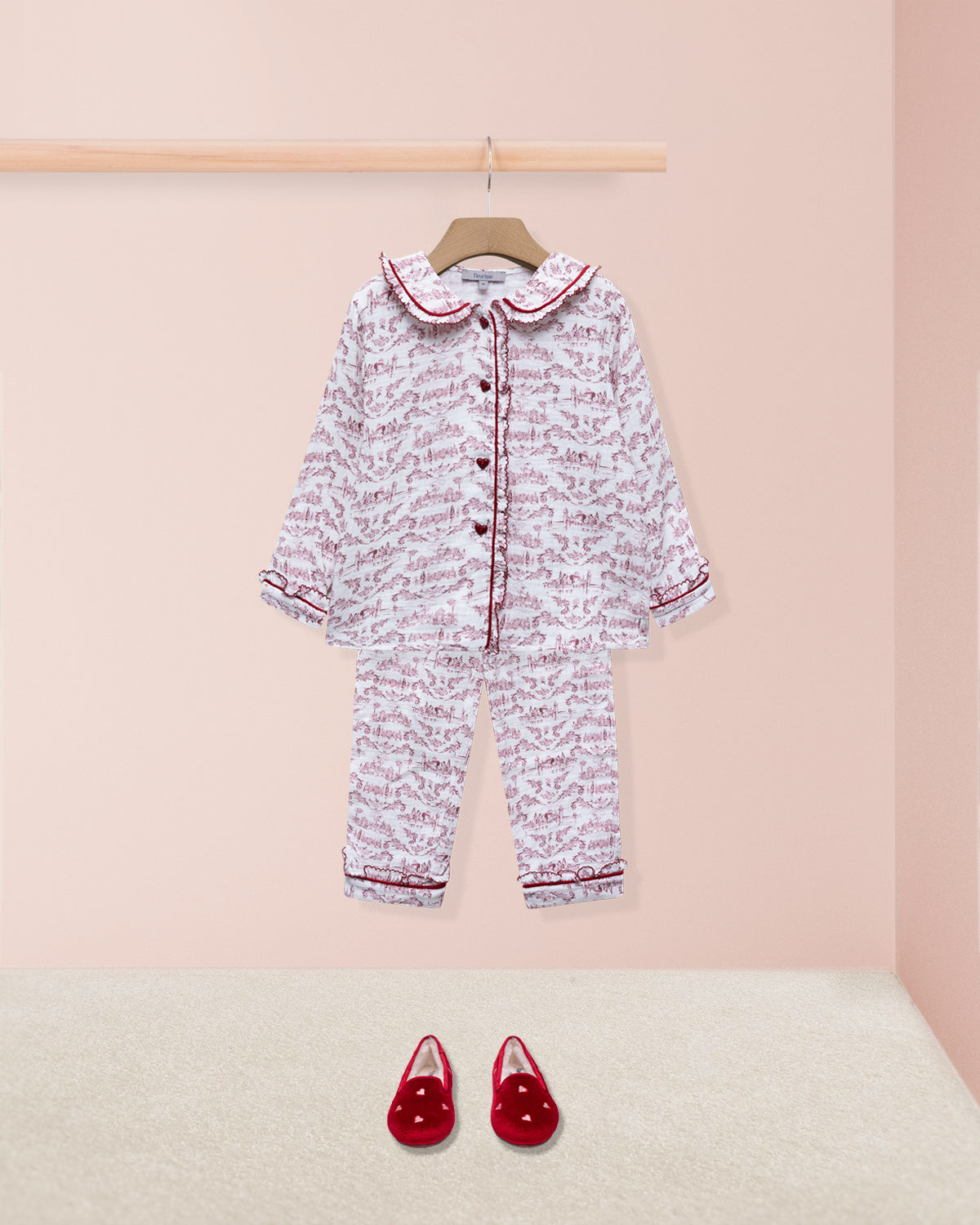 Children's pajama set with floral pattern and red shoes on a pink background