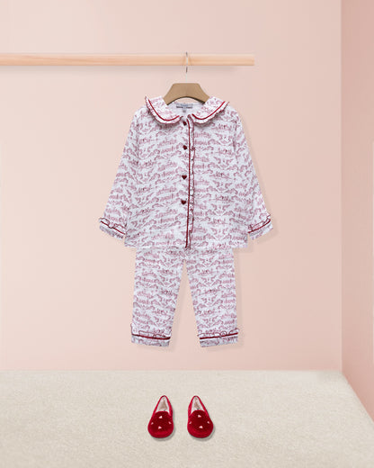 Children's pajama set with floral pattern and red shoes on a pink background