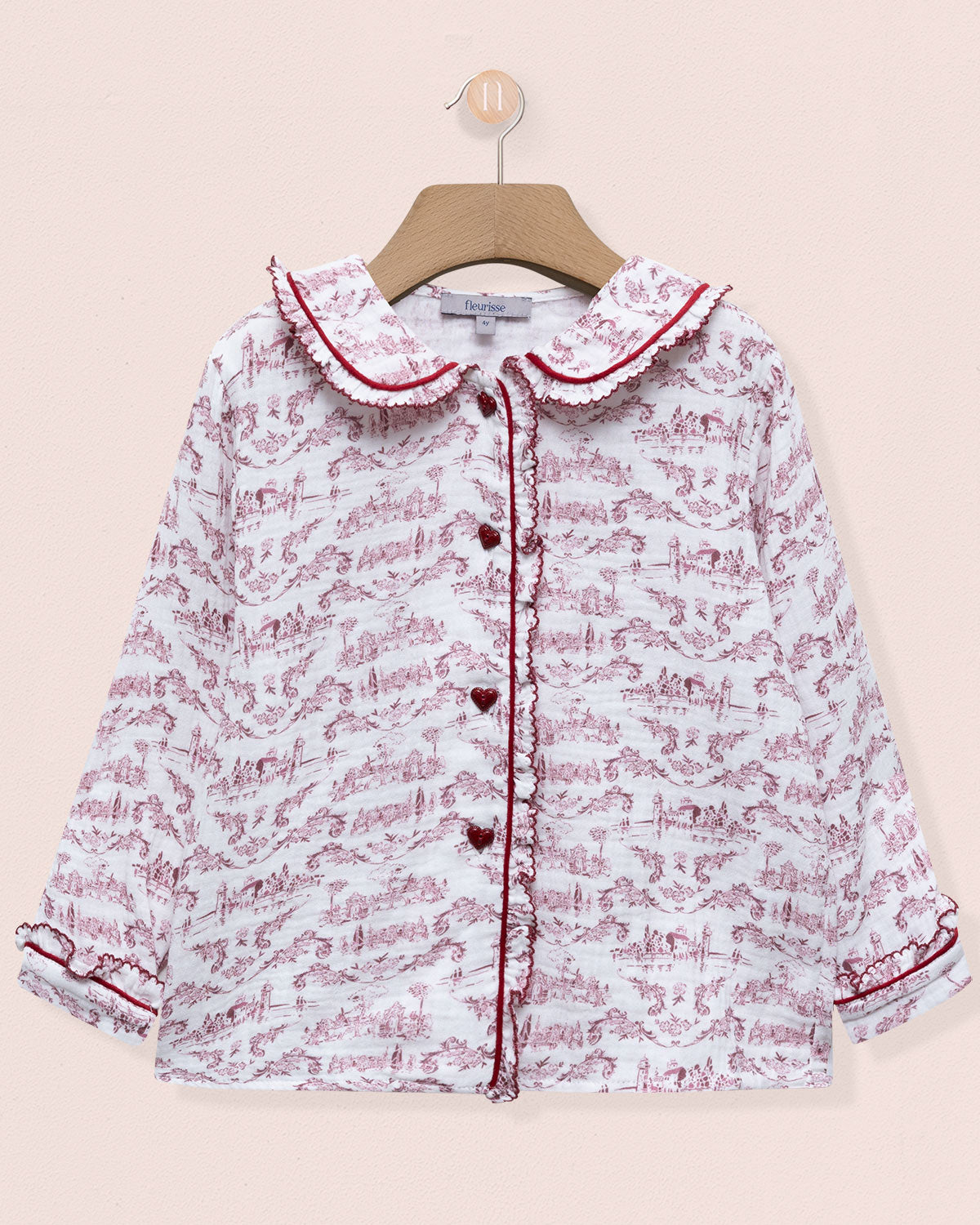 Floral patterned baby girl's shirt on a hanger against a light pink background