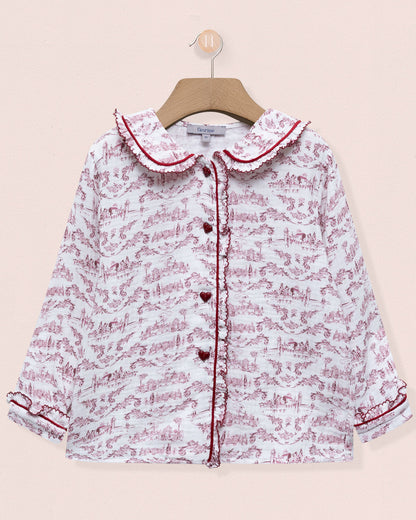 Floral patterned baby girl's shirt on a hanger against a light pink background
