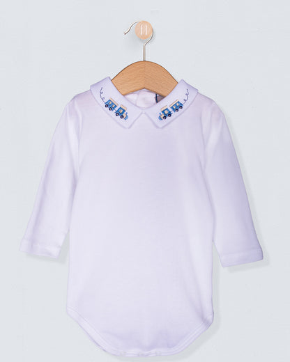 White baby shirt with embroidered collar on a wooden hanger against a light gray background