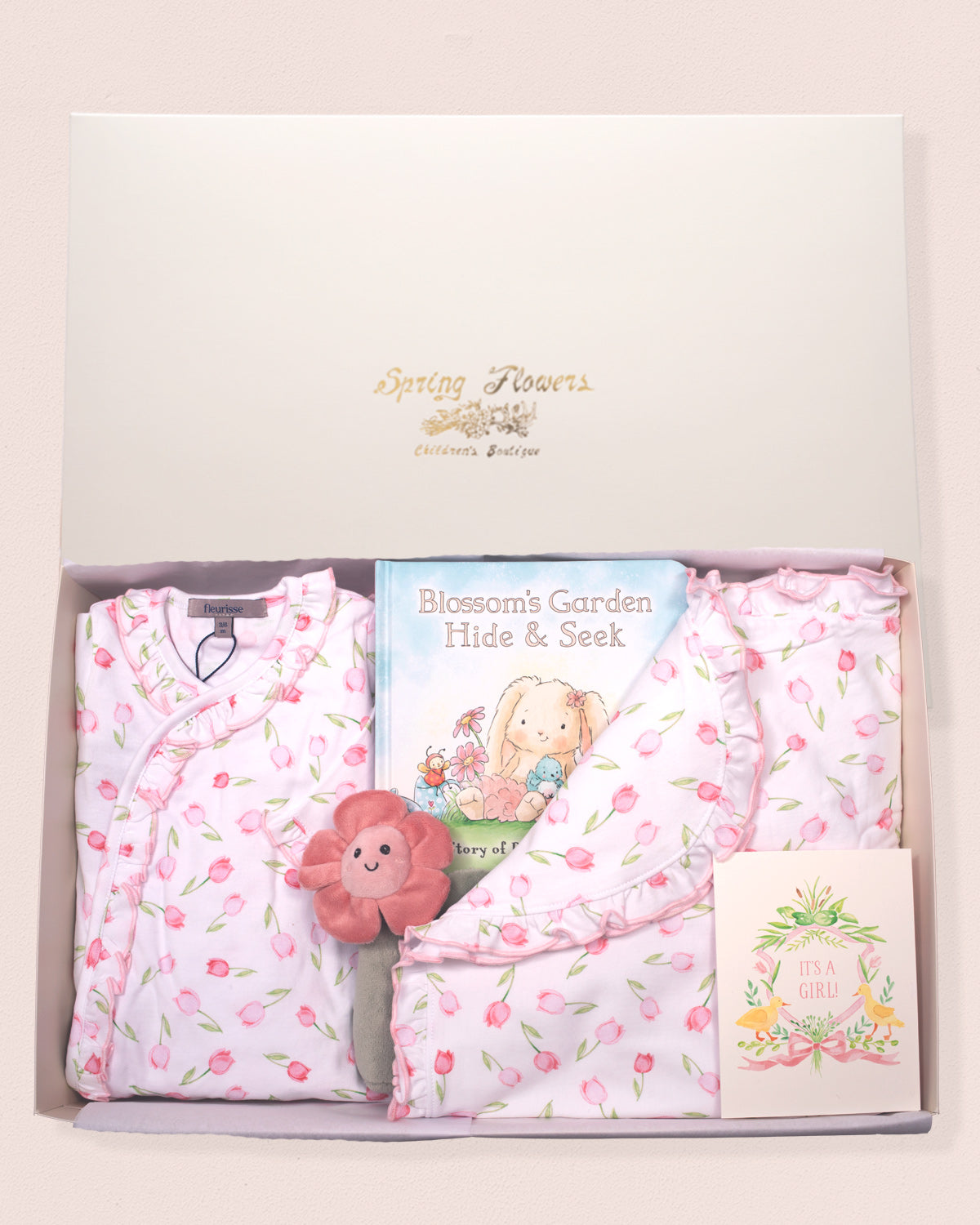 Baby gift set with floral baby clothes, a book, and a plush toy in a decorative box.