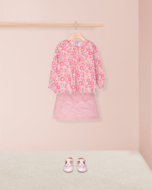 Pink floral top and skirt set with matching shoes on a pink background