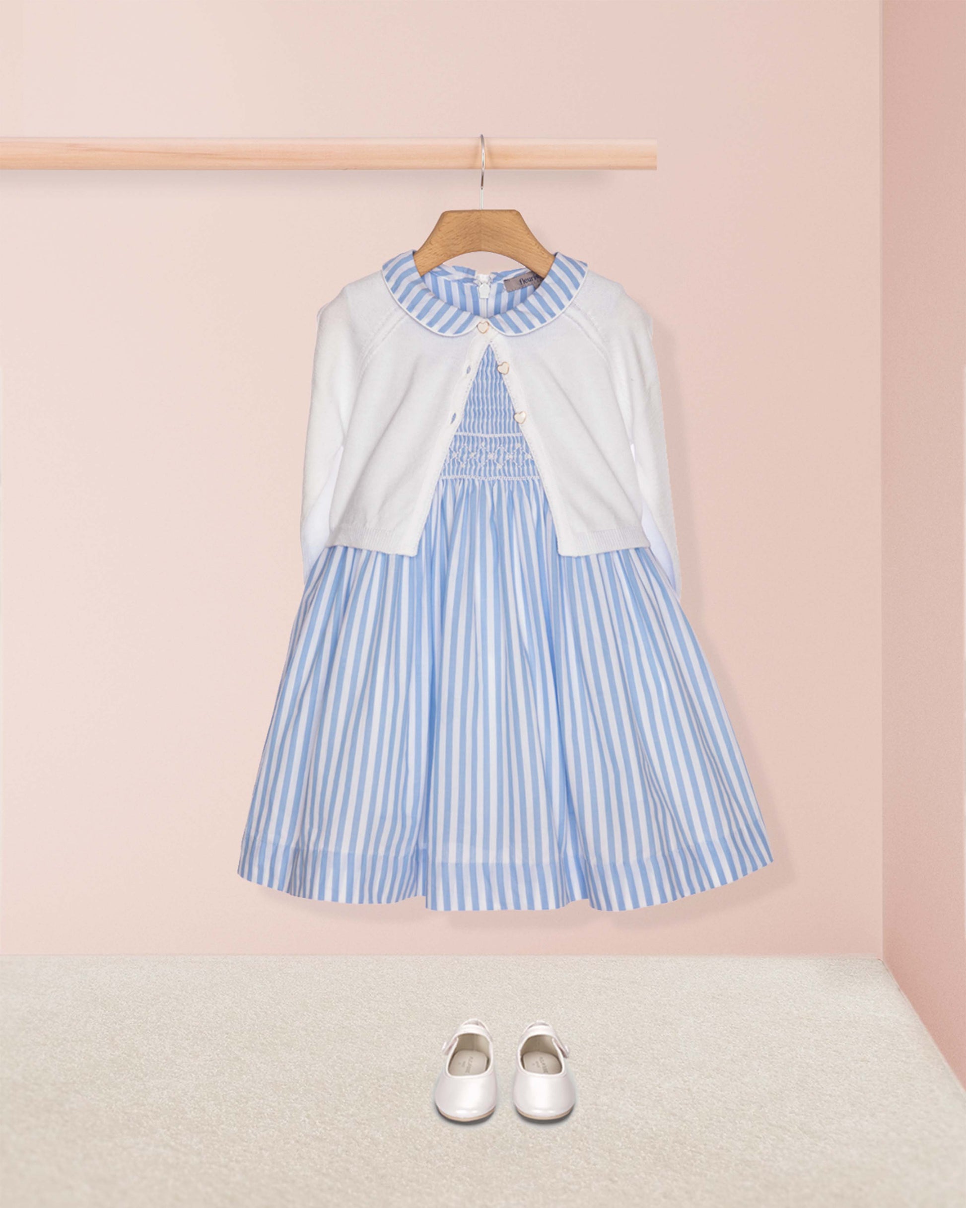 Blue and white striped dress with a white cardigan on a pink background