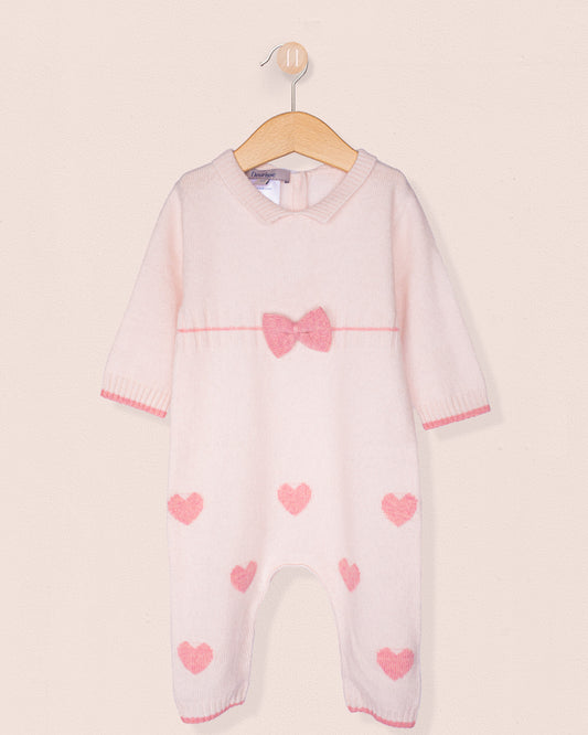 Front of cashmere baby onesie with pink hearts and a bow on a hanger against a light background