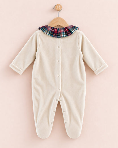 A cream-colored long-sleeve baby footed sleeper with a plaid collar, hanging on a wooden hanger against a soft pink background.