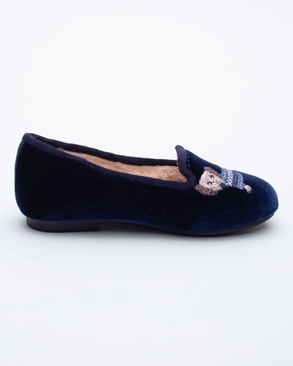 Navy blue velvet flat shoe with a decorative bow on a white background