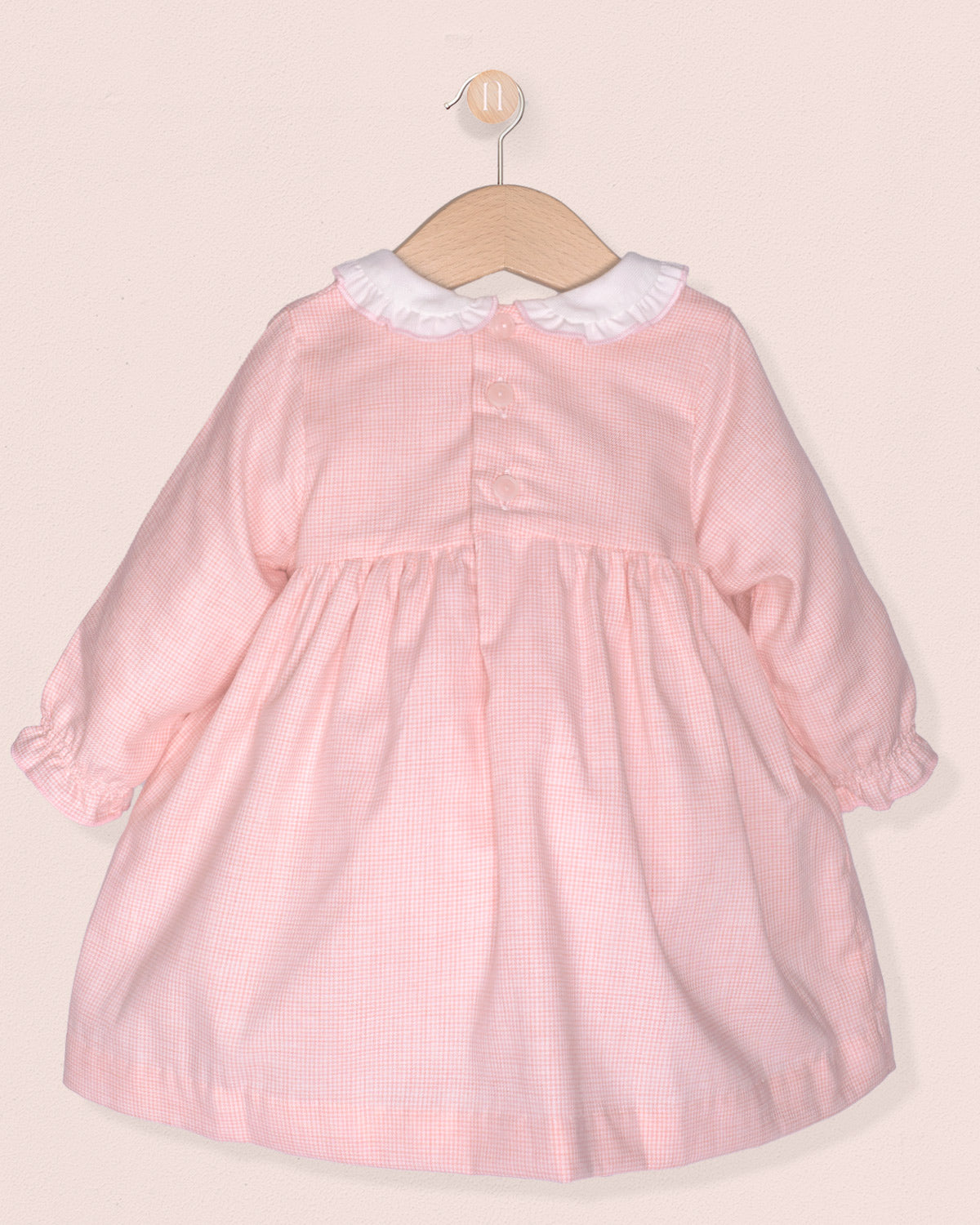 back of pink dress with smock and white collar on hanger on pink background