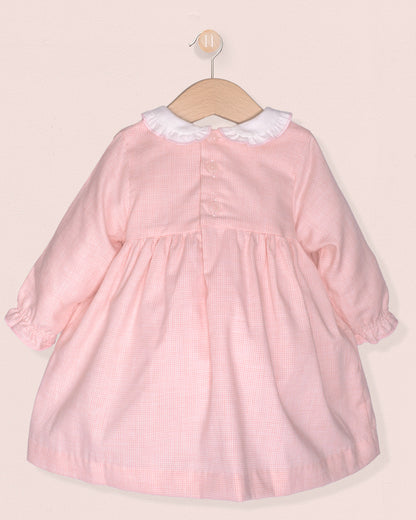 back of pink dress with smock and white collar on hanger on pink background