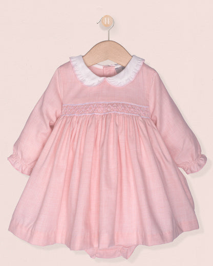 pink dress with smock and white collar on hanger on pink background