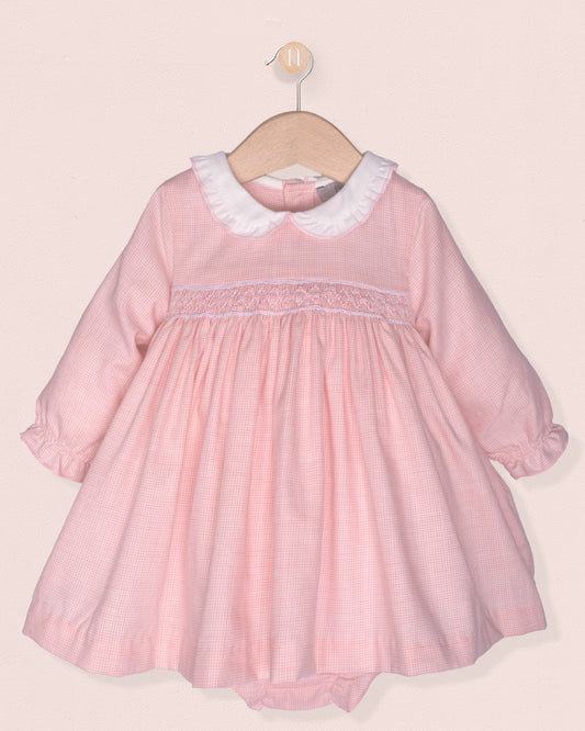 pink dress with smock and white collar on hanger on pink background