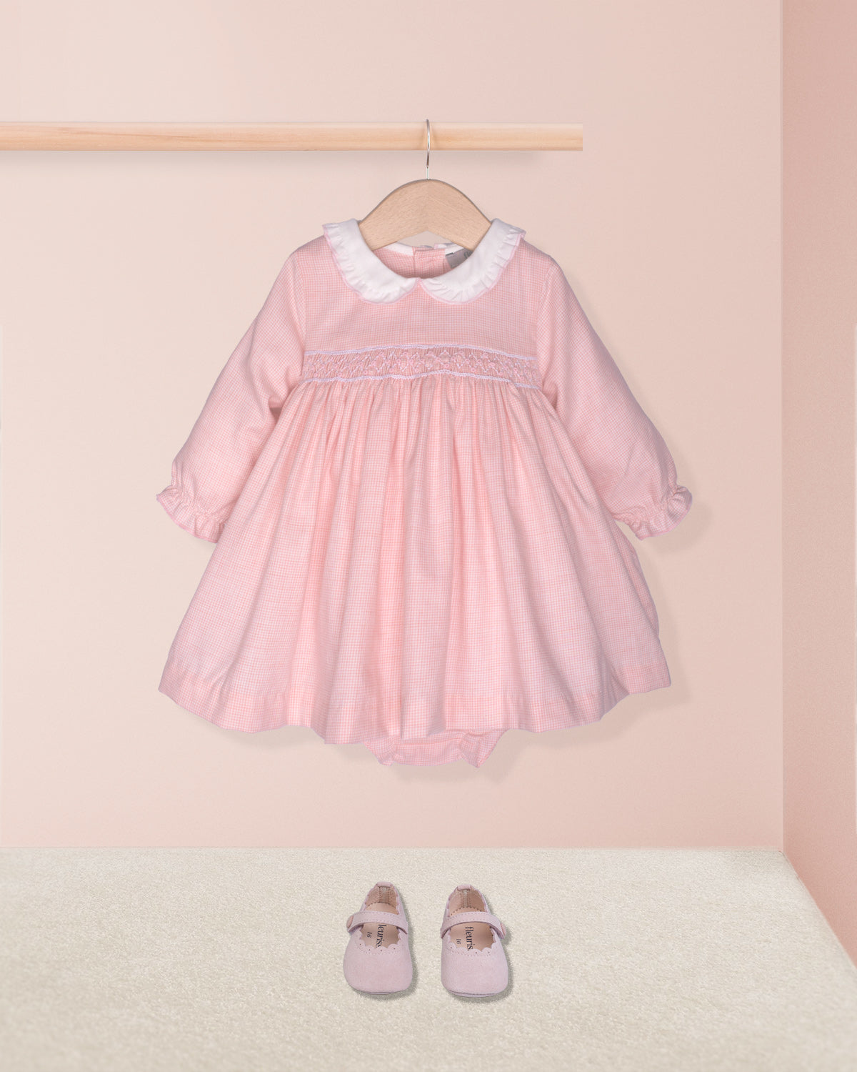 pink dress with smock and white collar on hanger on pink background with shoes